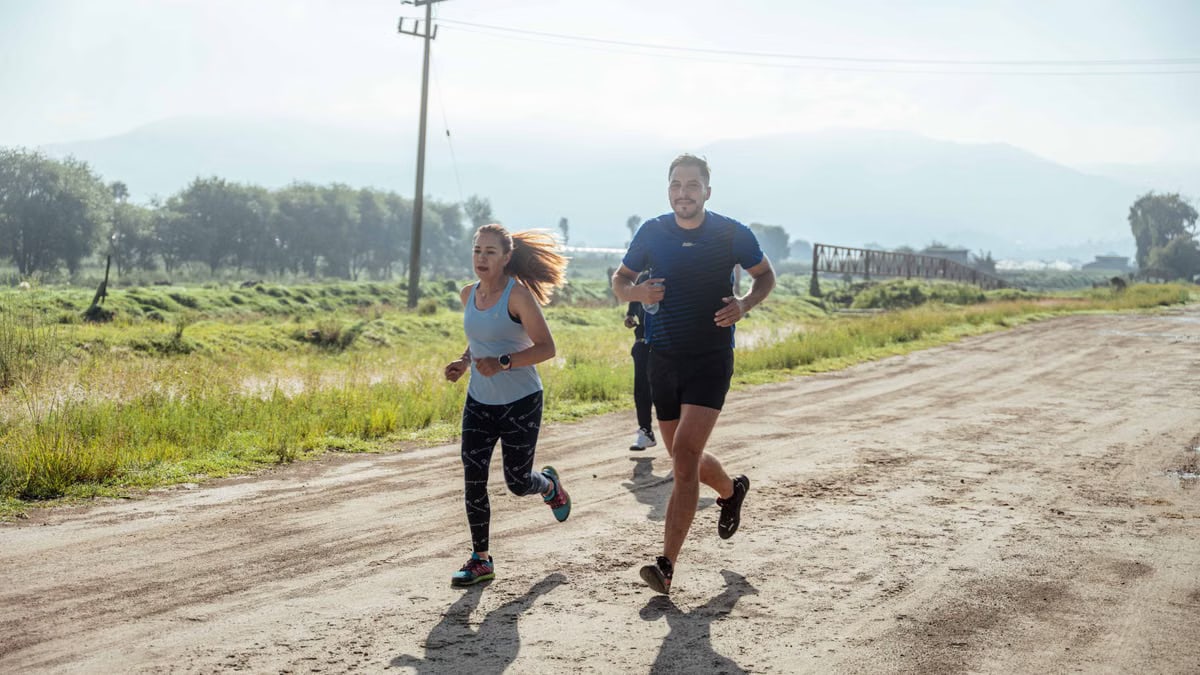 Group of joggers running along a rural dirt path surrounded by nature.